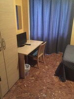 A small room with a desk, chair, and a bed.