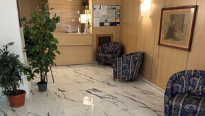 Eine Lobby mit Marmorboden, Holzvertäfelung, einem Empfangstresen und gemusterten Stühlen.