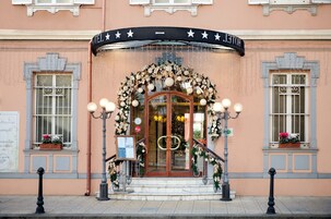 Entrada de hotel con un amplio arco, un cartel sobre la puerta y una escalera que conduce a ella.