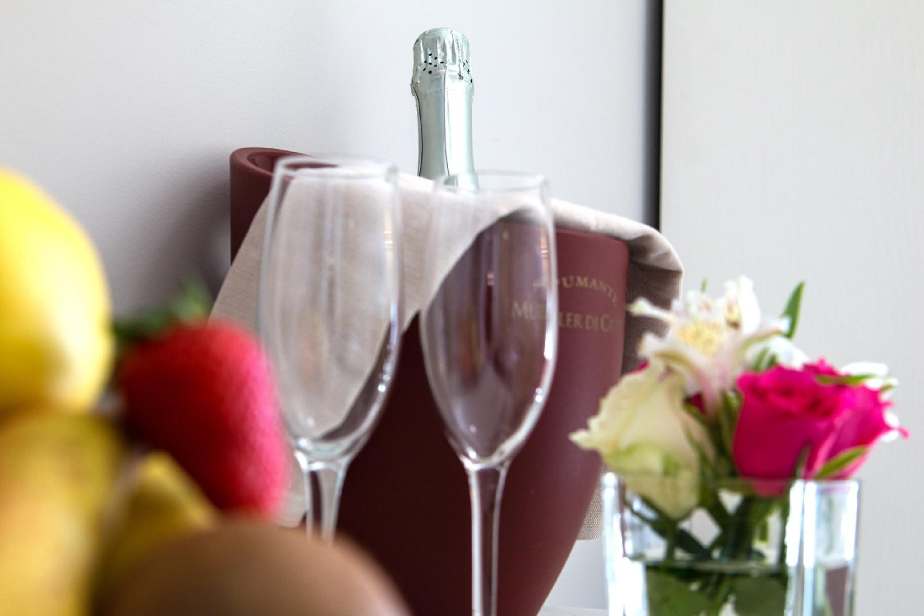 A bottle of champagne, two glasses, and a book titled "MUMMERS" on a table.