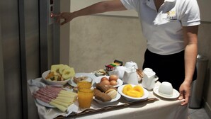 Un bufé de desayuno con diversos alimentos y una persona atendiendo.