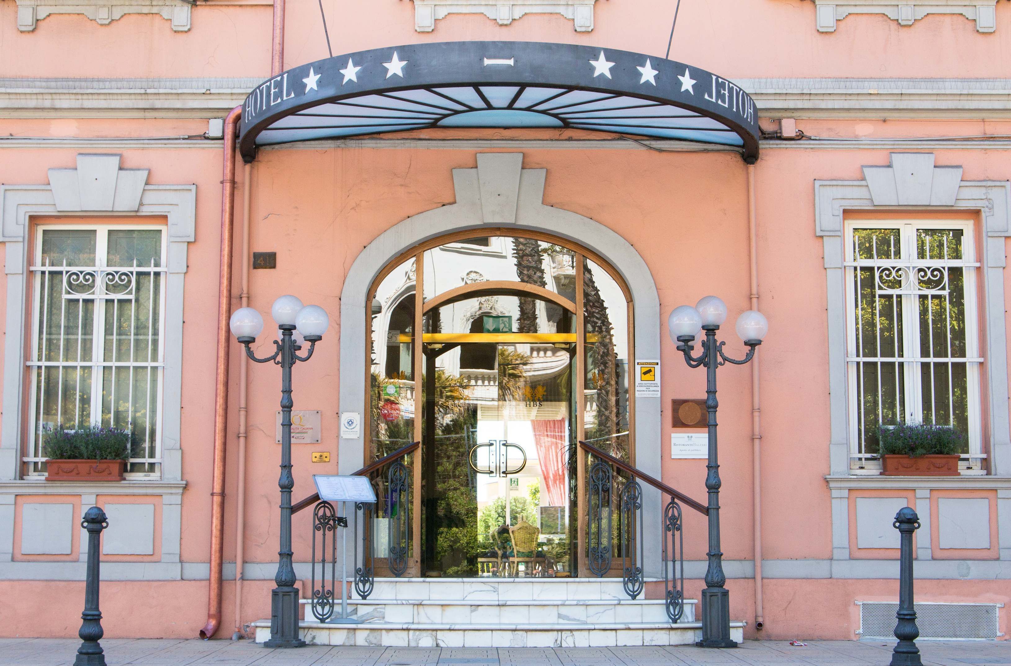 Entrada de hotel com arco decorado com estrelas, porta de vidro e escadaria.