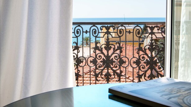 Una habitación con vistas al mar a través de barandillas de hierro ornamentales.