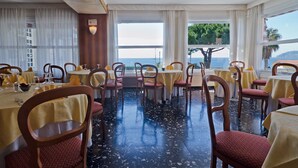 Een restaurant met ronde tafels, stoelen en uitzicht op zee.
