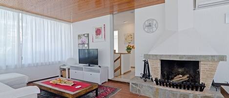 A modern living room with a fireplace, white furniture, and artwork on the walls.