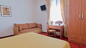 Ett hotellrum med en säng, en soffa, ett skrivbord, en stol och en garderob.