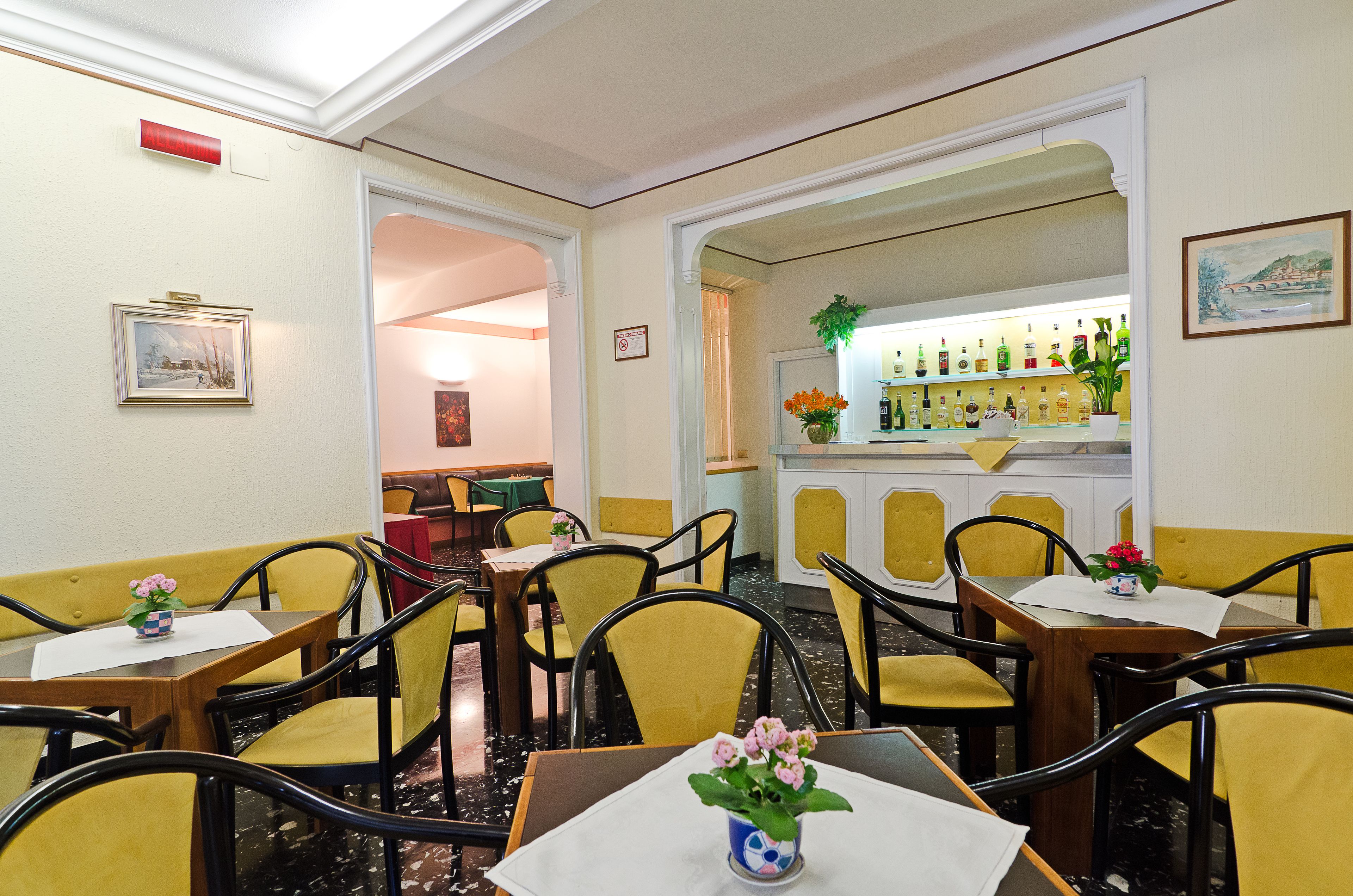 Un restaurant avec des chaises et des tables jaunes, ainsi qu’un bar où sont exposées des bouteilles.