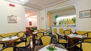 Un restaurant avec des chaises et des tables jaunes, ainsi qu’un bar où sont exposées des bouteilles.