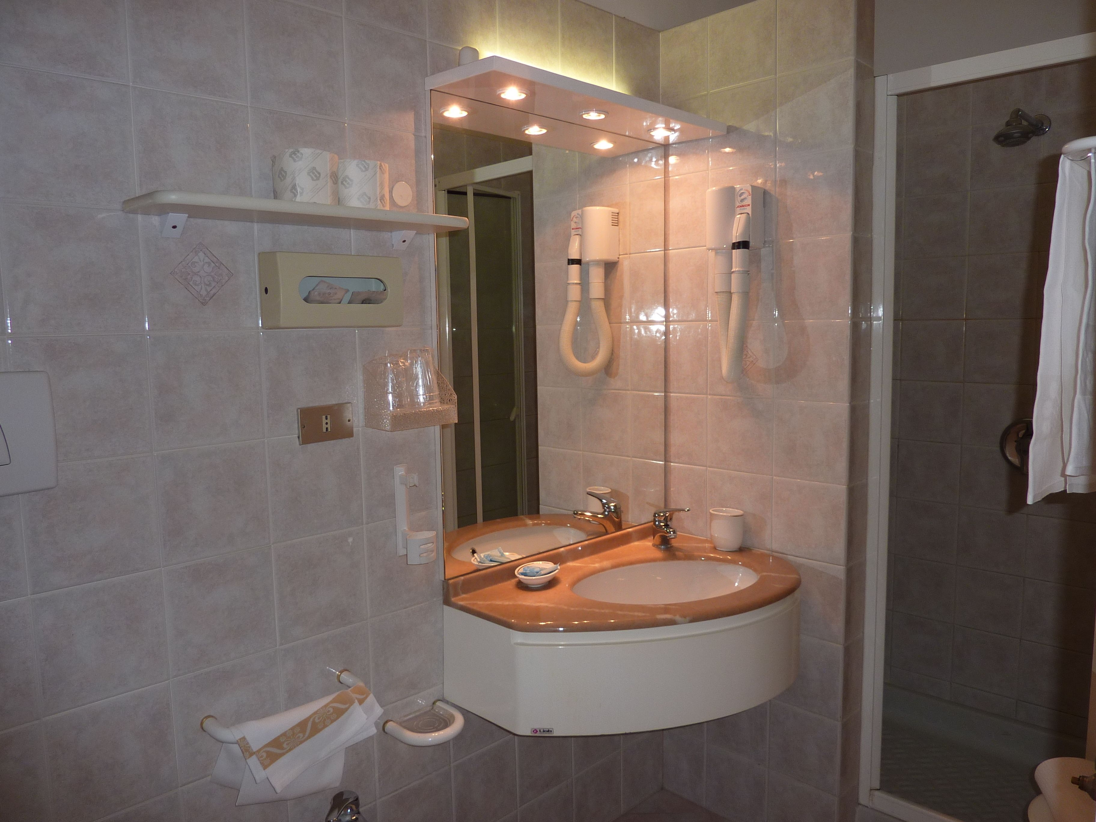 Un baño con lavabo, espejo, inodoro y ducha.