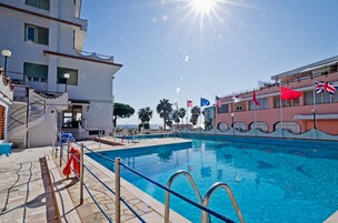 Una piscina al aire libre, sombrillas, sillones reclinables de piscina