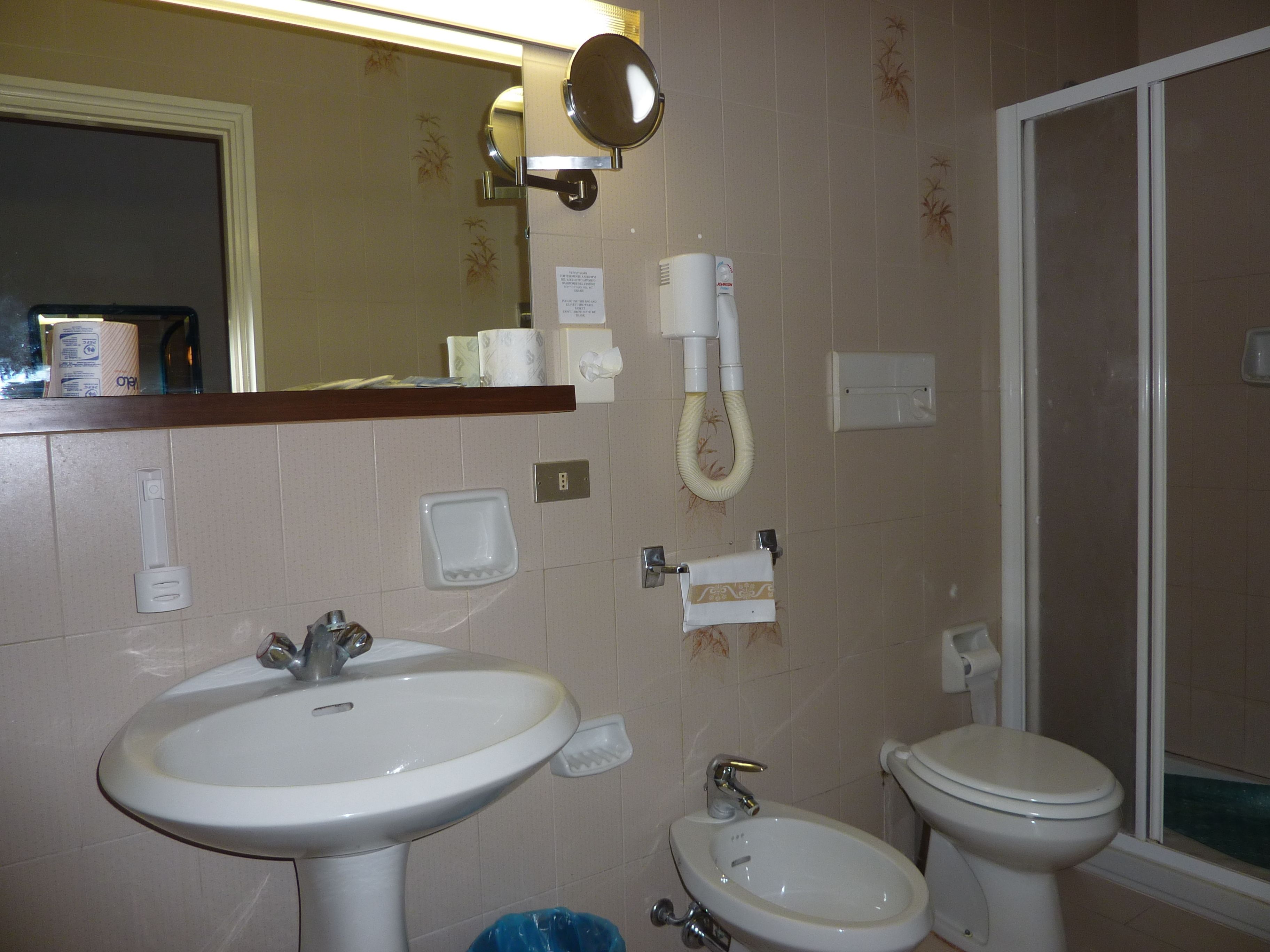 A bathroom with a sink, bidet, toilet, and a mirror.