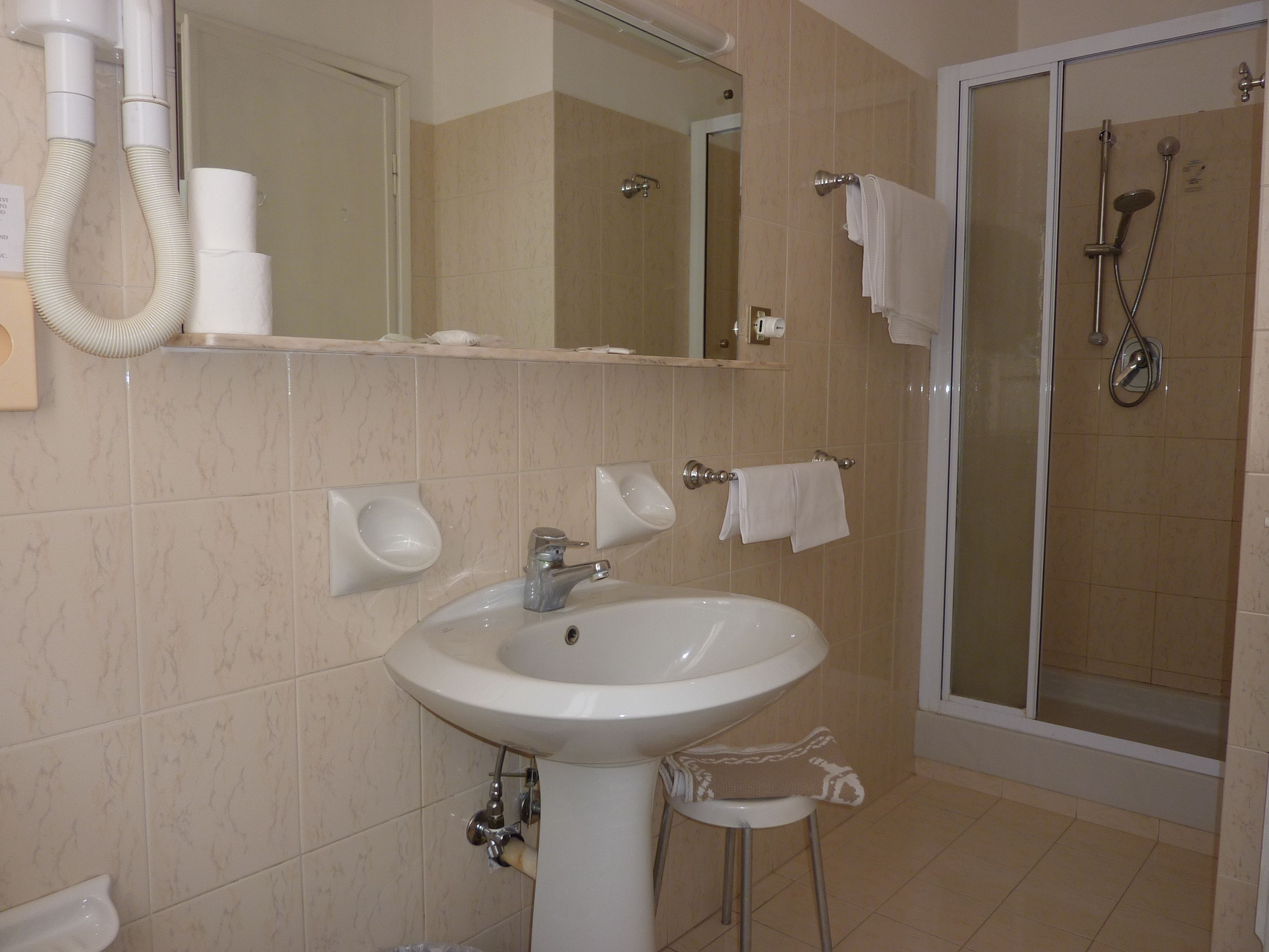 A bathroom with a sink, mirror, towel rack, and shower.