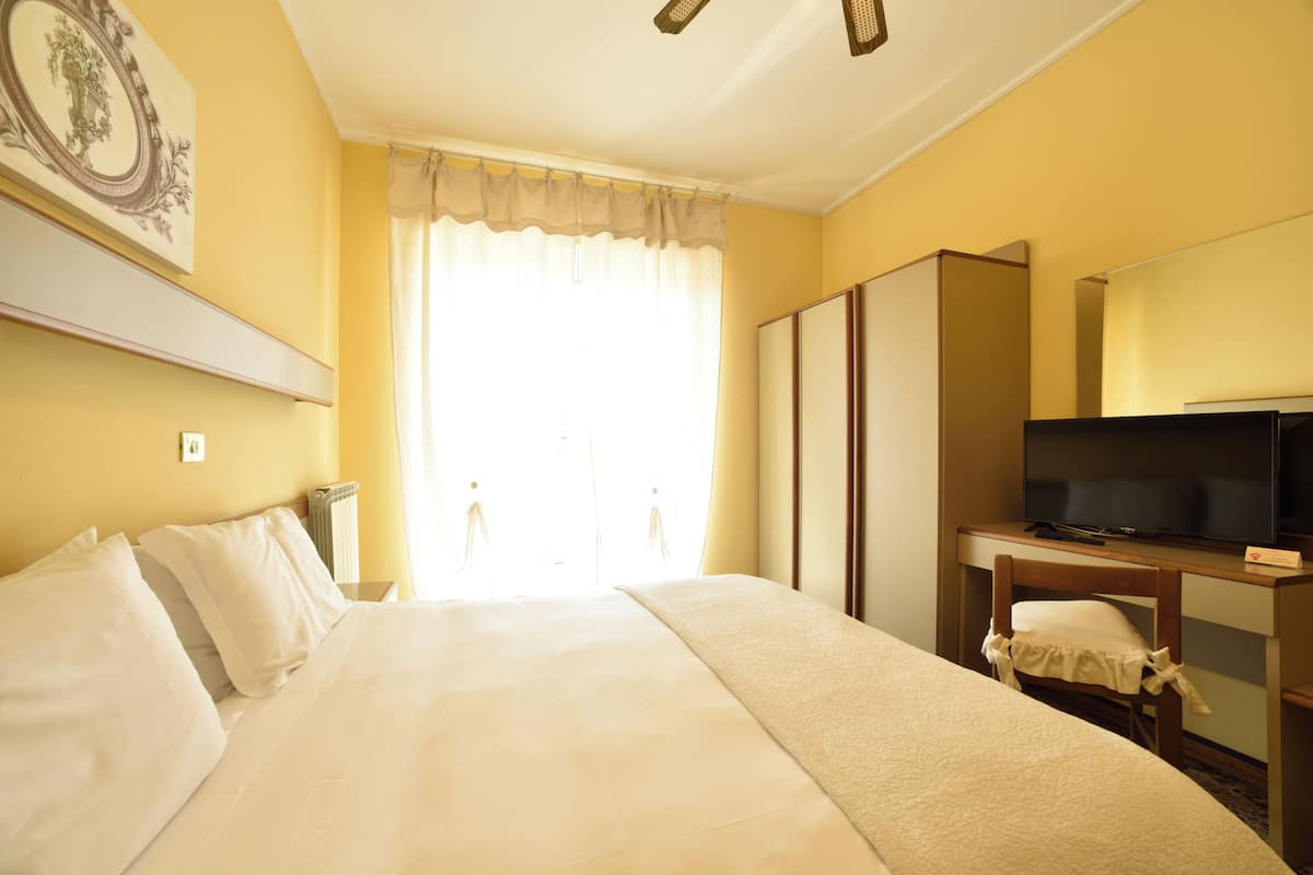 Une chambre d’hôtel avec un grand lit, une télévision, un bureau et une armoire.