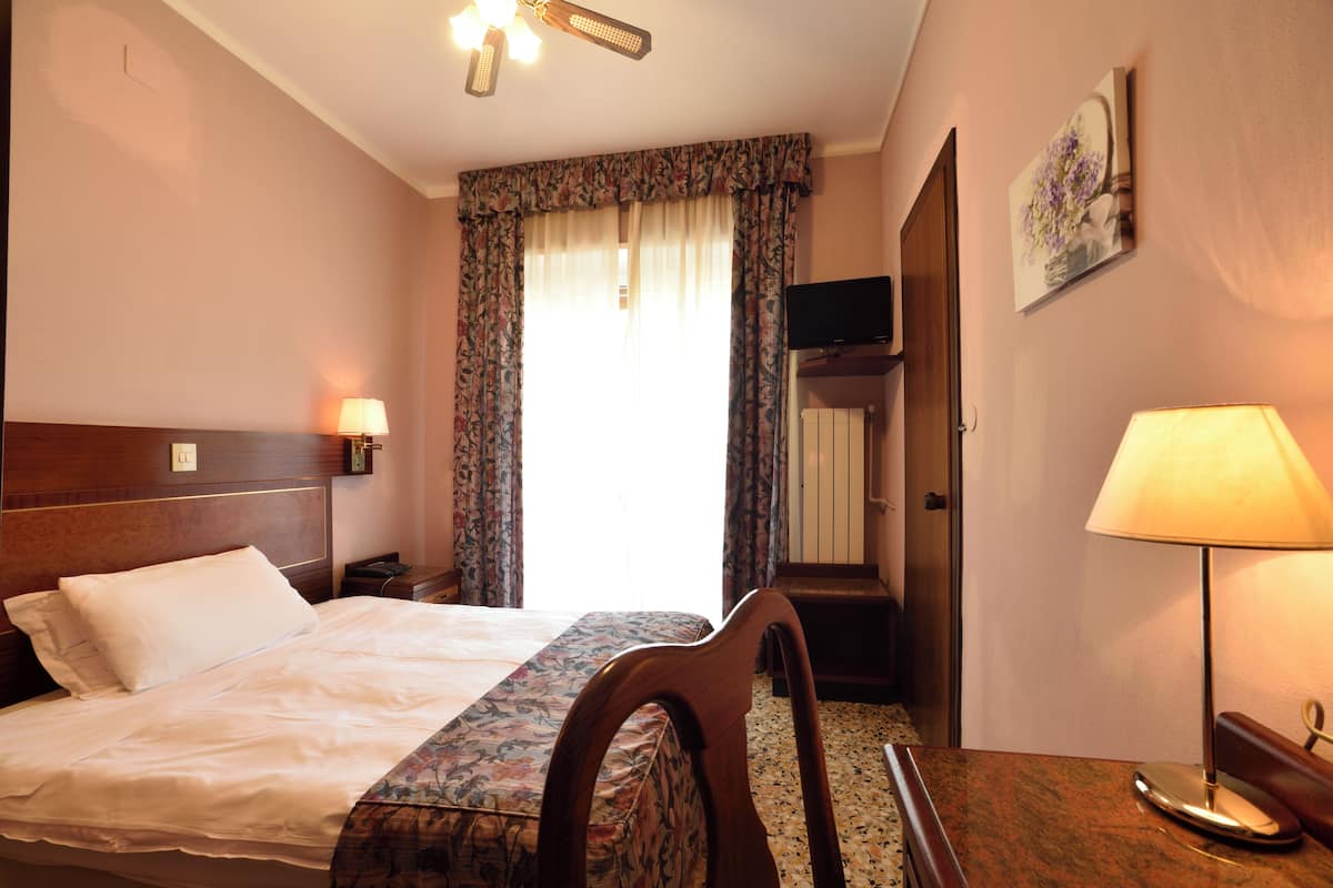 Une chambre d’hôtel avec un lit, un bureau, une chaise, une télévision et une porte.