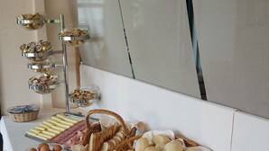 Una mesa de buffet con diversos alimentos, incluyendo pan, pasteles y carnes.