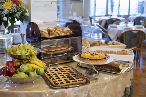 A buffet table with various food items including fruits, pastries, and a cake.