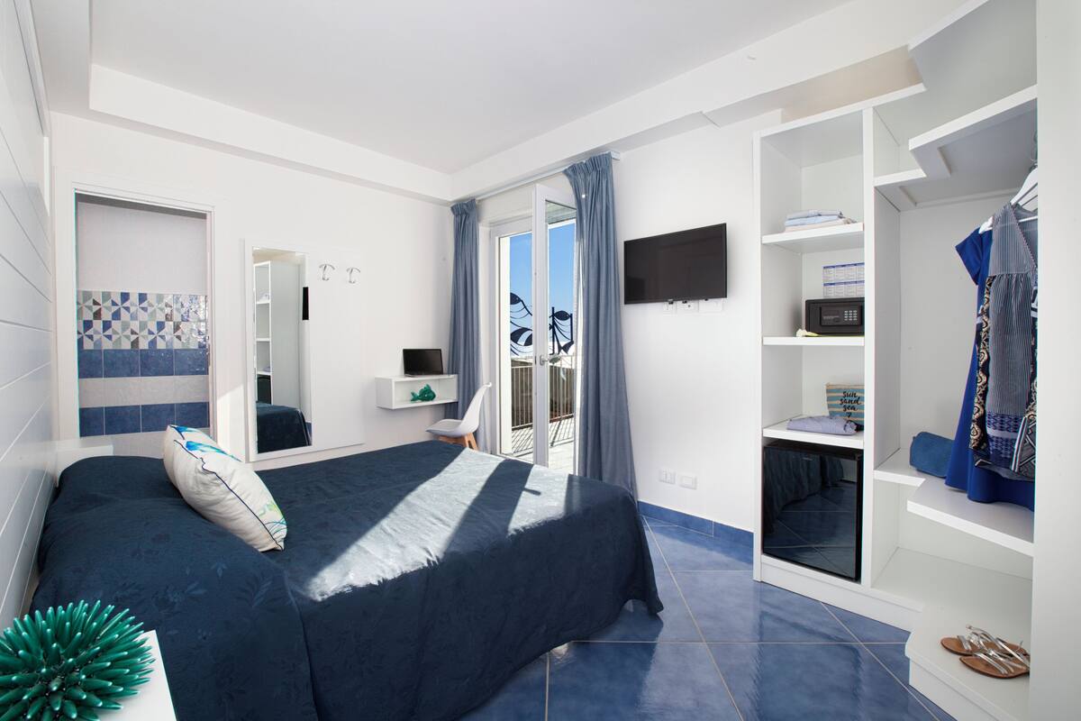 Un dormitorio con cama, televisión, armario y balcón.
