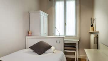 A bedroom with a bed, a desk, a chair, a wardrobe, and a radiator.