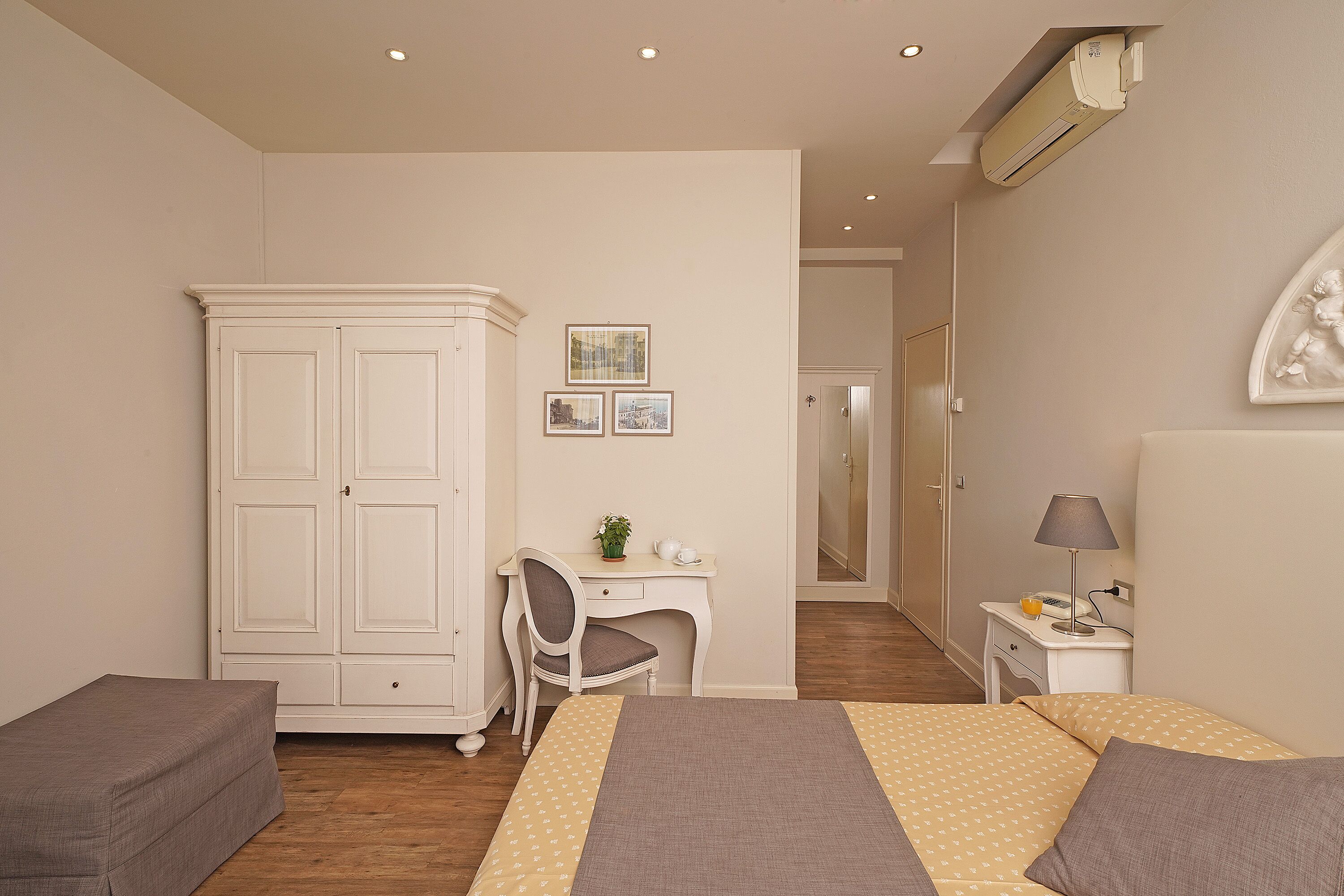 A bedroom with a bed, a desk, a chair, a wardrobe, and a nightstand.