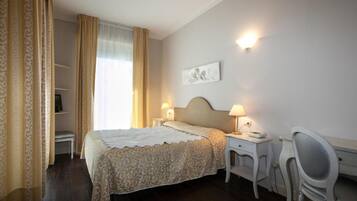 Une chambre d’hôtel avec un lit, des tables de chevet, un bureau et une chaise.