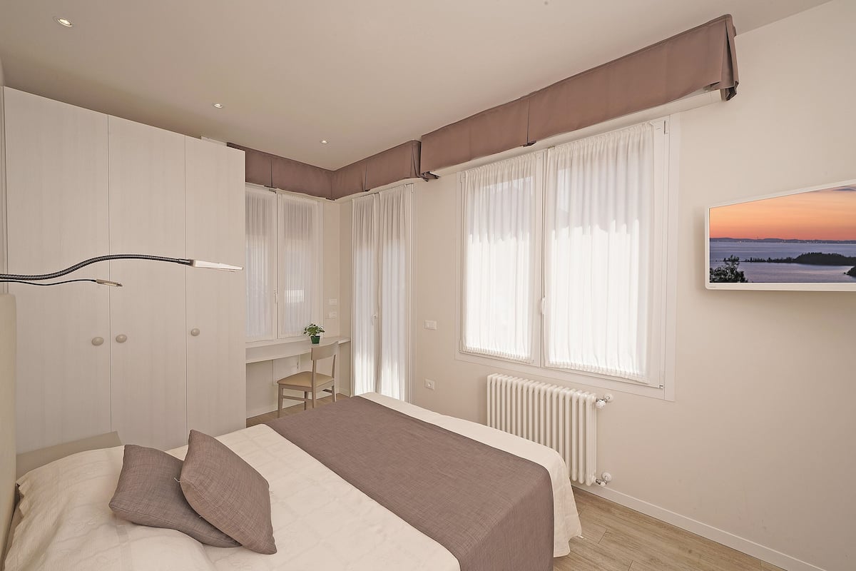 A bedroom with a bed, a desk, and a radiator.