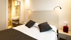 A hotel room with a bed, bedside table, nightstand, and a bathroom visible through an open door. - Hotel Marconi (Sirmione)