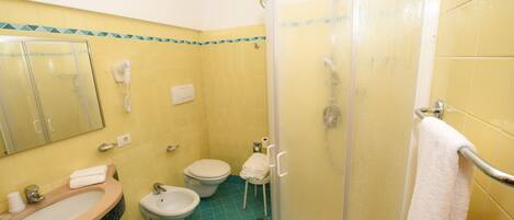 Un baño con lavabo, bidé, inodoro y ducha con mampara de vidrio.