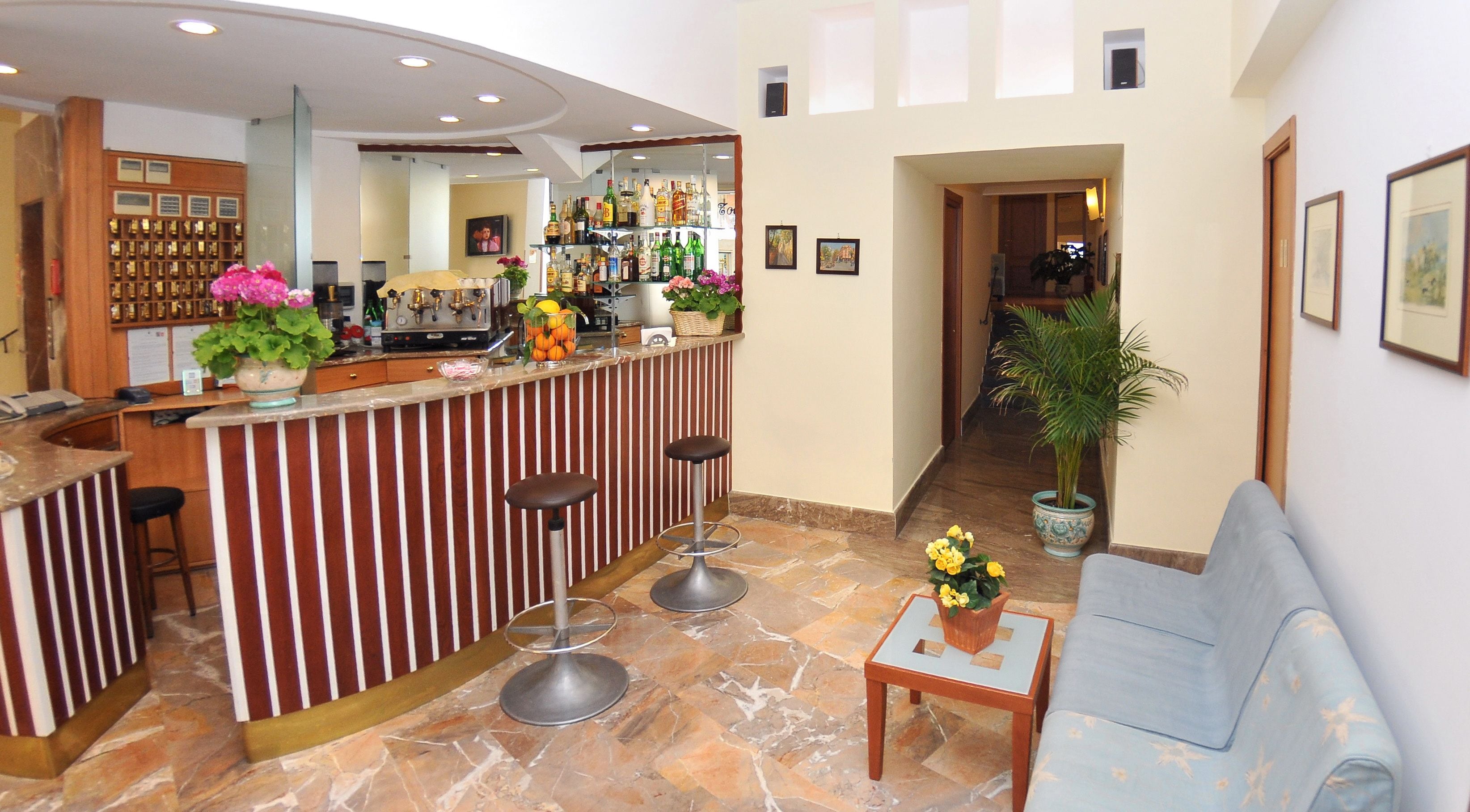 Eine Bar mit Theke, Hockstühlen und einer Zimmerpflanze.