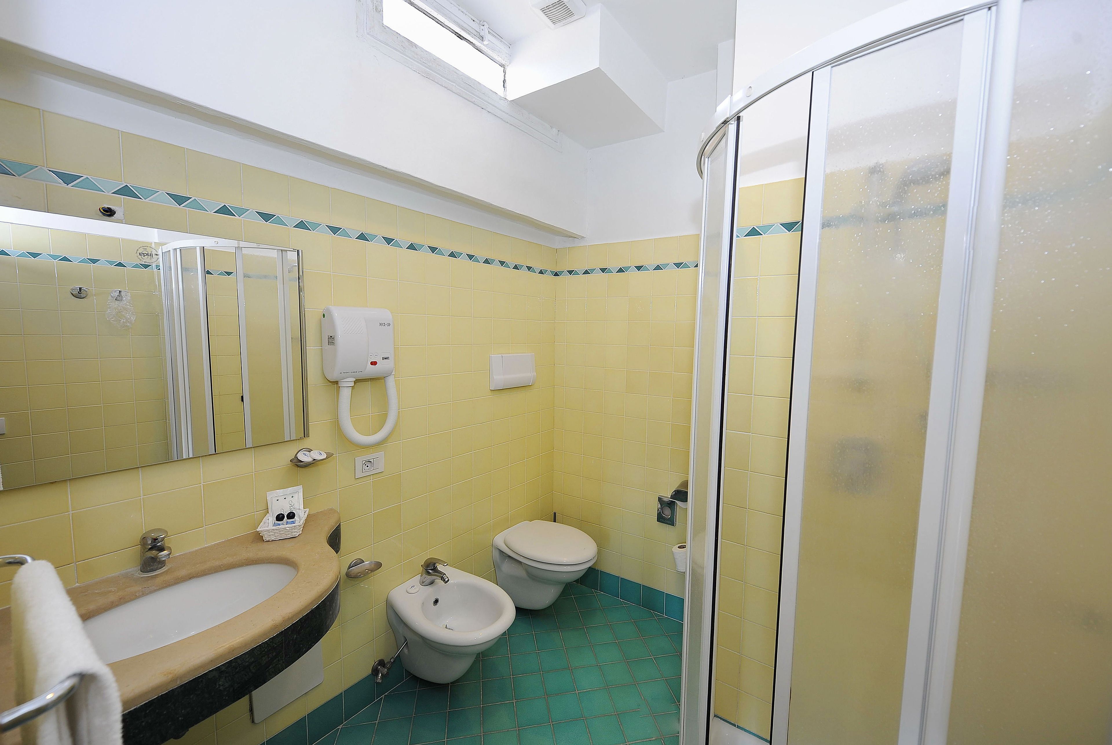 A bathroom with a sink, two toilets, a shower, and a mirror.
