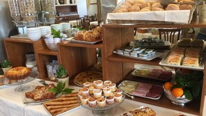 Un bufé con diferentes opciones de comida, incluyendo pasteles, sándwiches y postres.