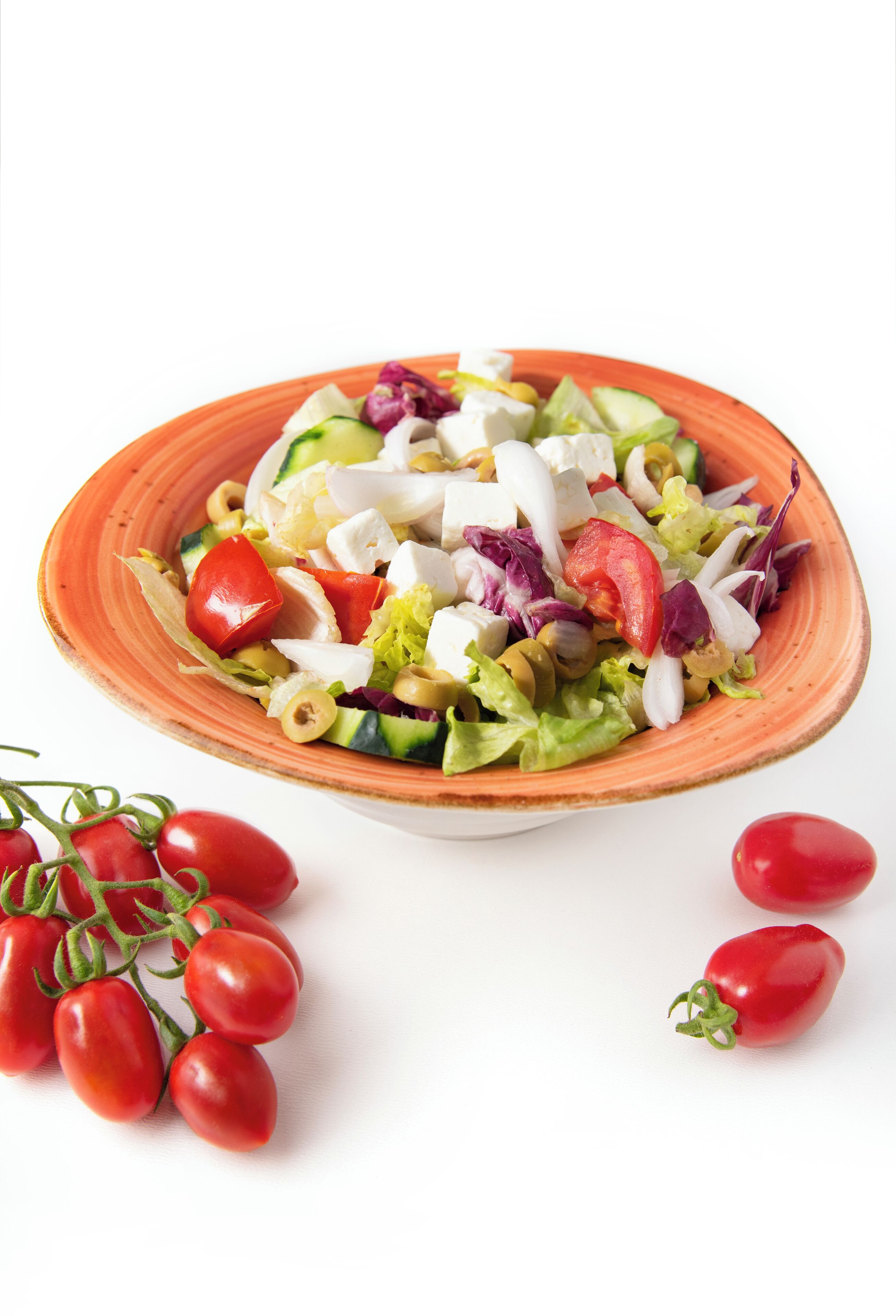 A bowl of salad with various vegetables and a plate of cherry tomatoes.