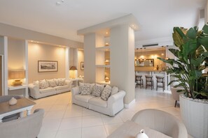 A modern living room with a sofa, chairs, a coffee table, and a large potted plant. - Hotel Capri - Adult Only (Sorrento)