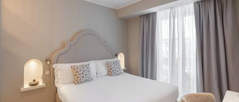 A hotel room with a bed, a desk, and a chair.