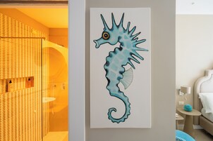 Un baño con cortina de ducha estampada, cabina de ducha de vidrio y lavamanos con artículos de aseo.