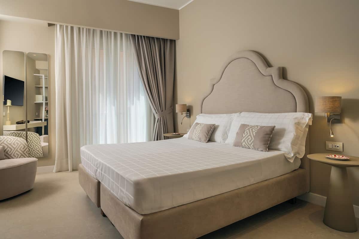 A spacious bedroom with a large bed, a bedside table with a lamp, and a chair.