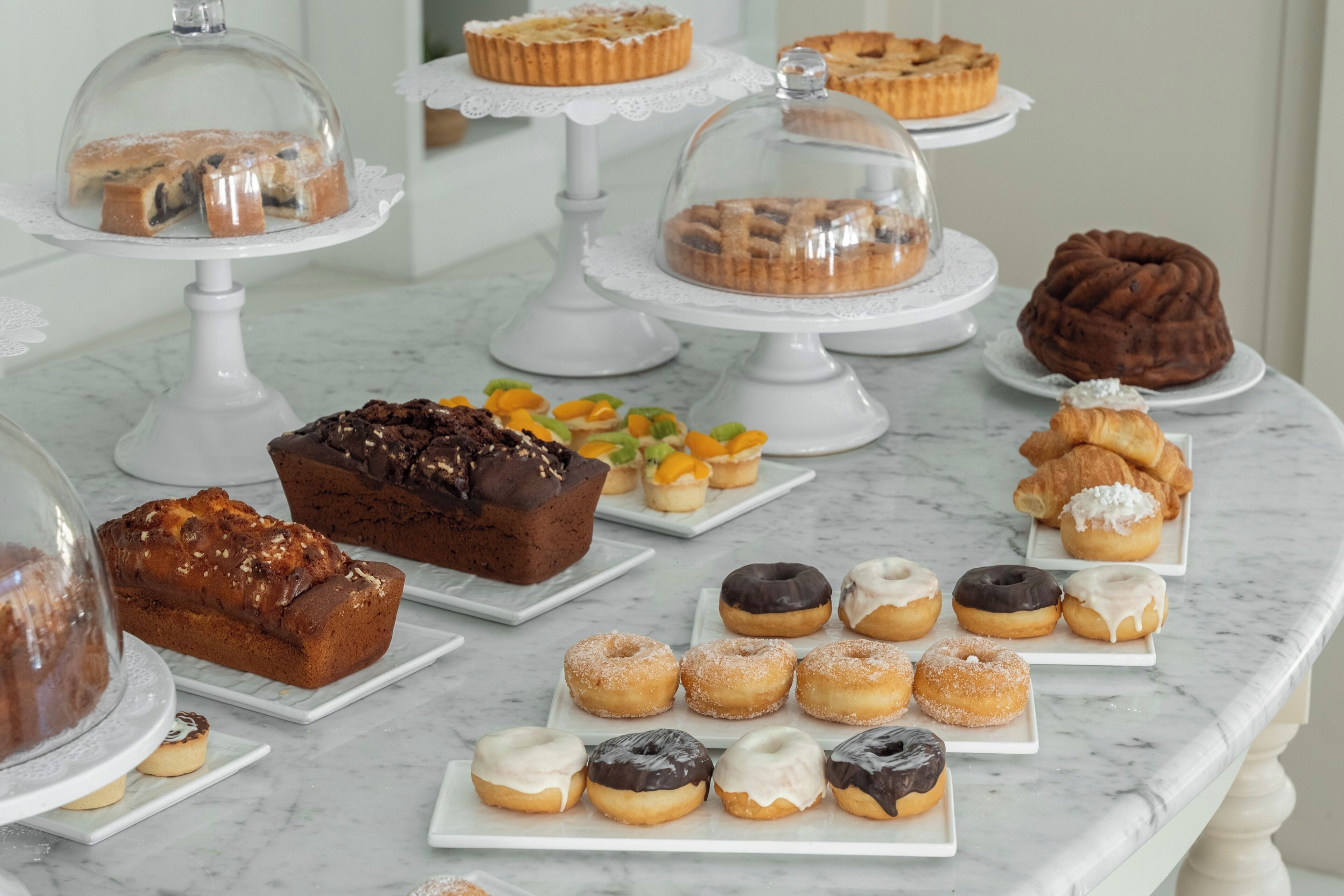 A variety of baked goods displayed on marble tables.