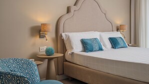 A neatly made bed with a headboard, two bedside lamps, and a small round table with a decorative item beside it. - Hotel Capri - Adult Only (Sorrento)