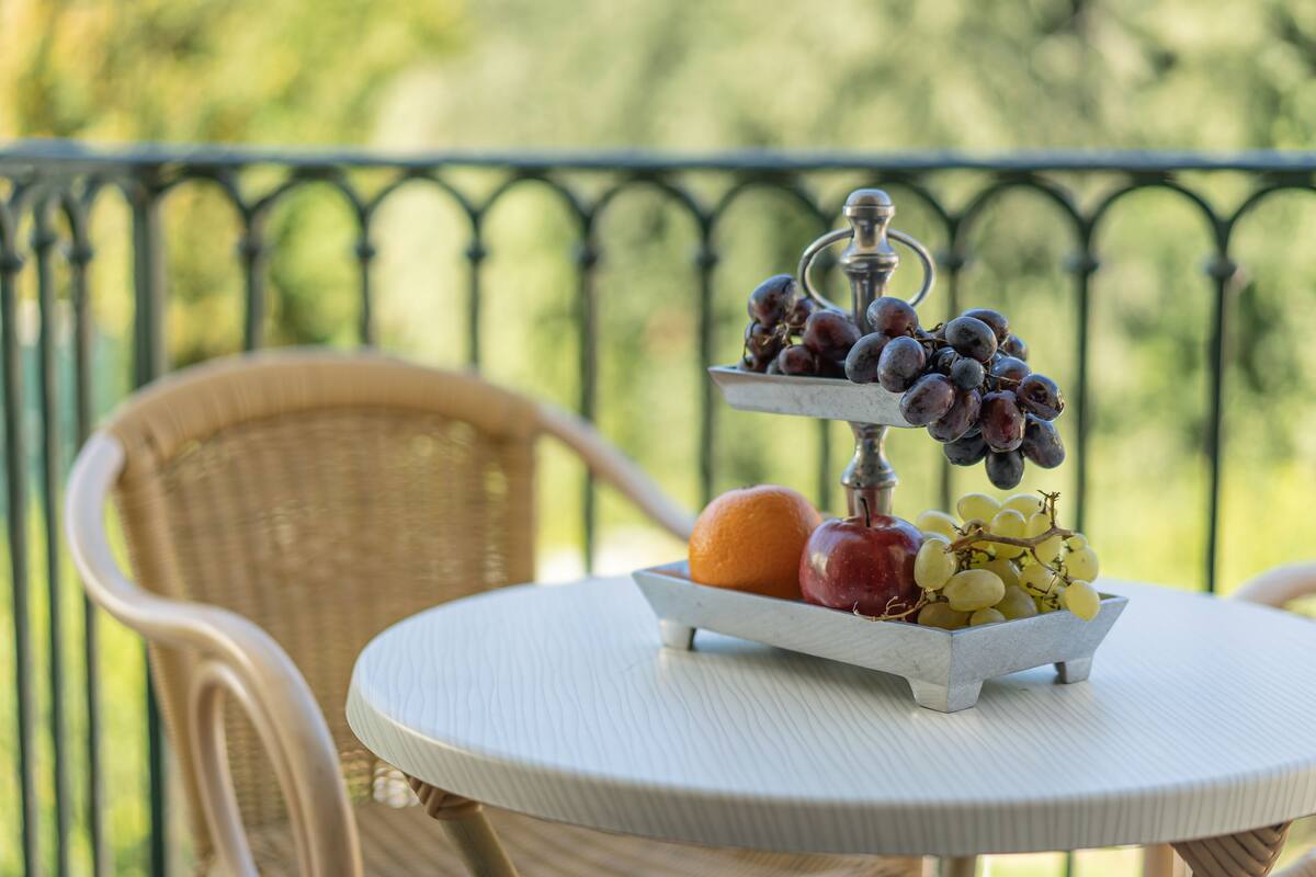 A round table with a fruit tray containing grapes, an apple, and an orange.