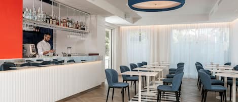 A modern restaurant with a bar area, seating arrangement, and a large window with curtains.