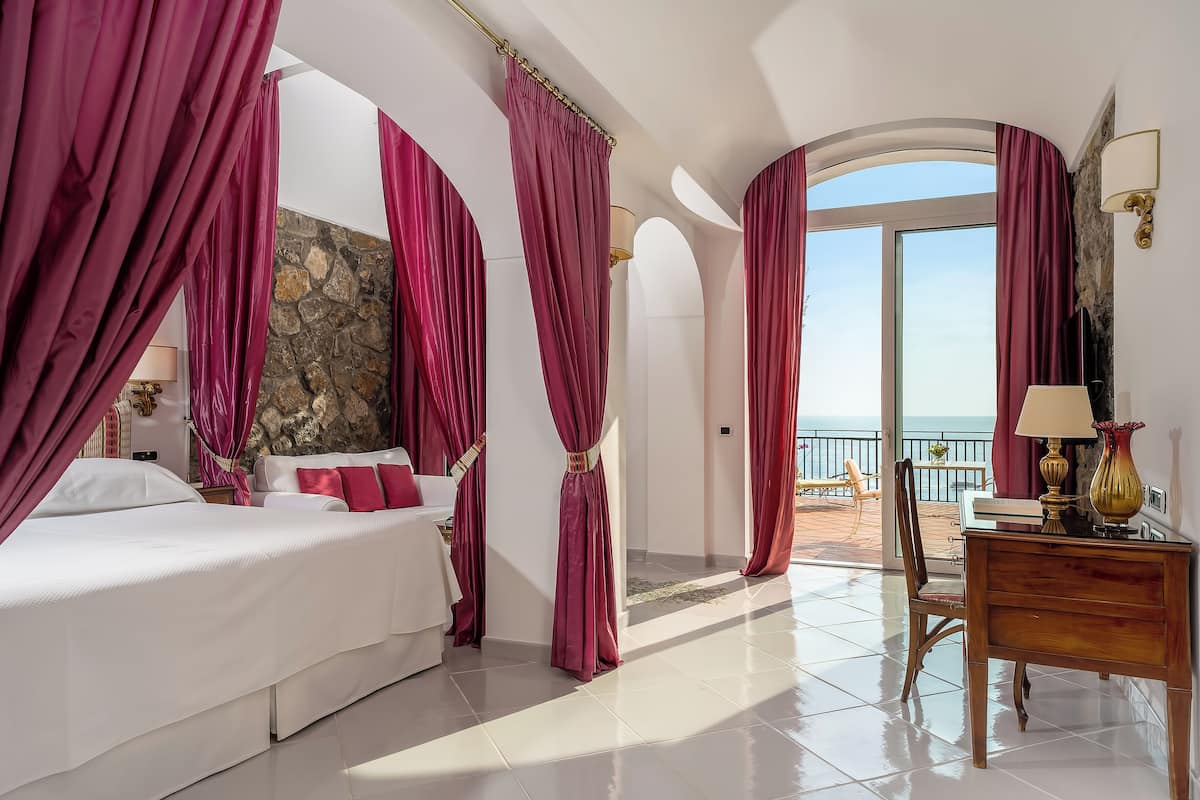 Ein Hotelzimmer mit Bett, Schreibtisch und Meerblick.