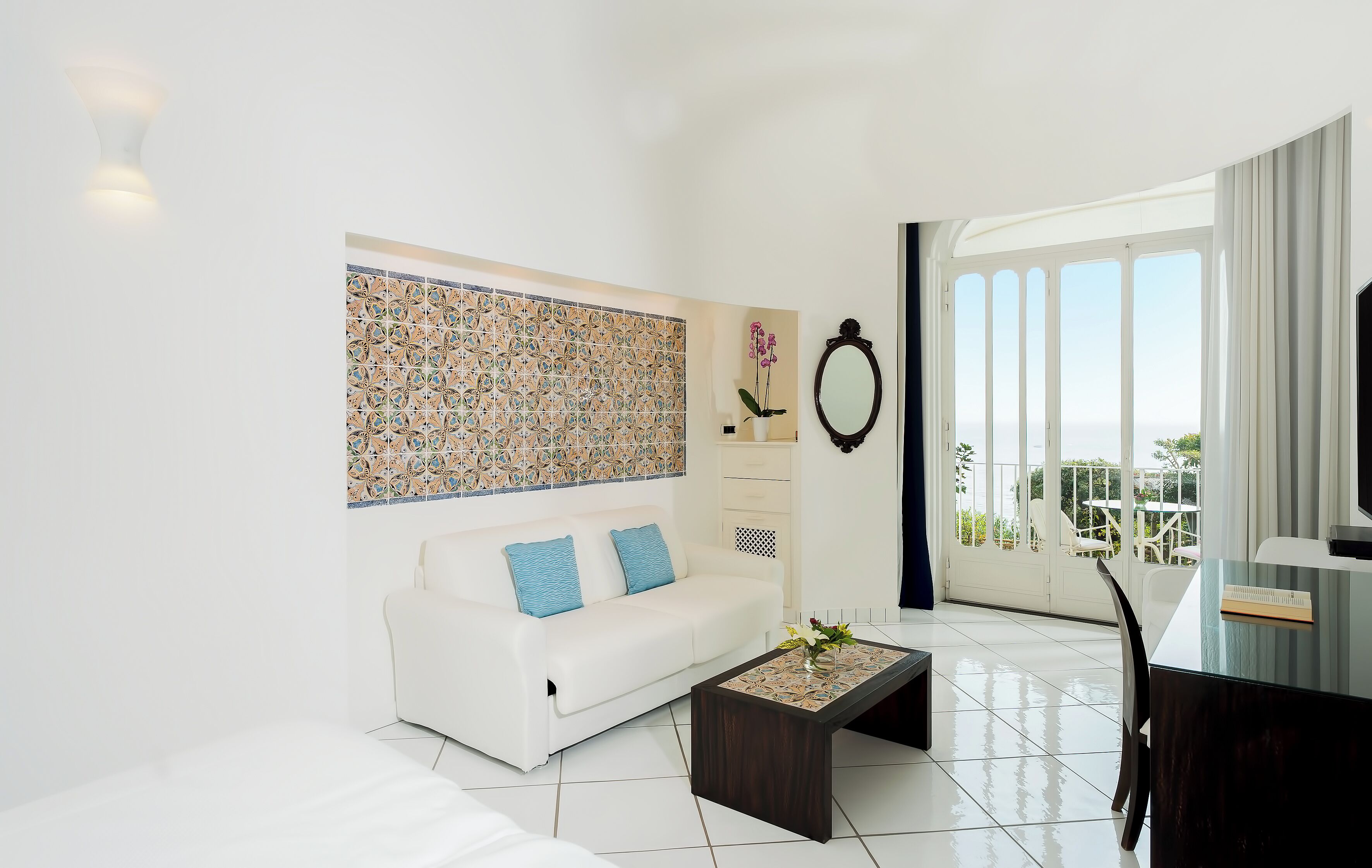 A modern living room with a white sofa, a coffee table, and a large window with a view.