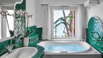 Une salle de bain avec une baignoire, un lavabo et une vue sur la mer par une fenêtre.