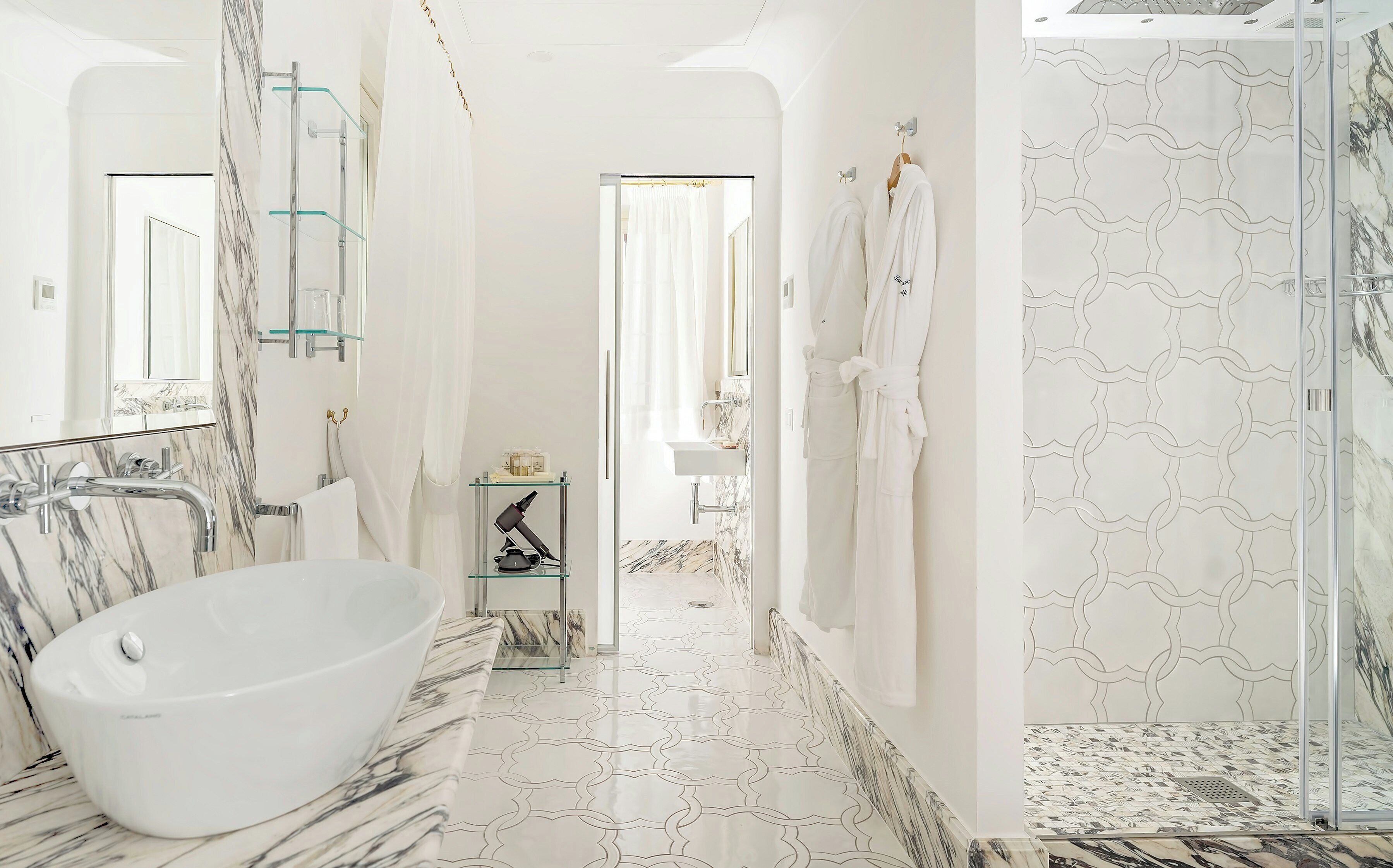 Ein modernes Badezimmer mit freistehender Badewanne, einer Duschkabine aus Glas und einem marmorverlegten Boden.