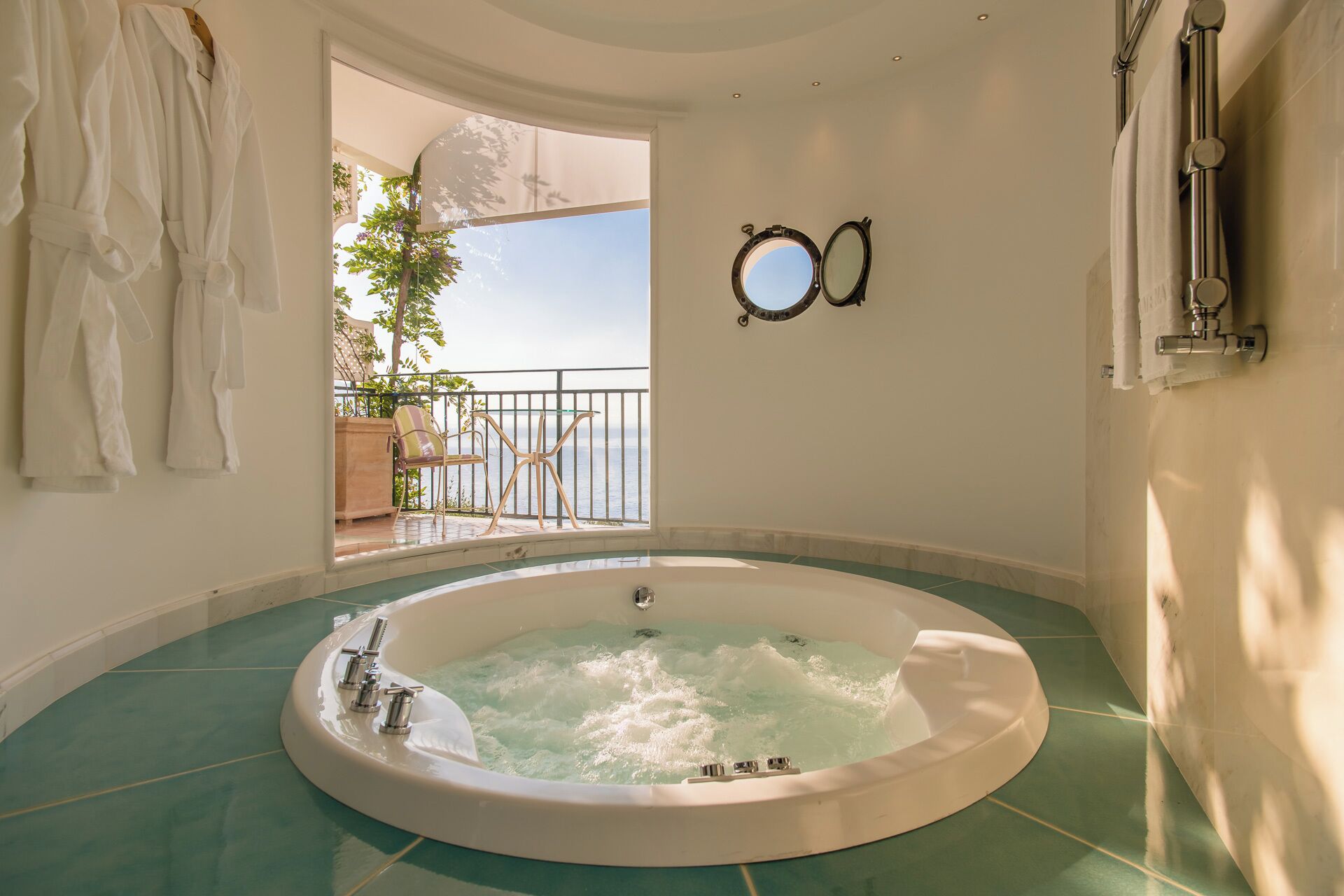 Ein geräumiges Badezimmer mit einer großen Badewanne, ein Balkon mit Meerblick und ein Spiegel an der Wand.