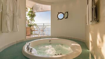 Ein geräumiges Badezimmer mit einer großen Badewanne, ein Balkon mit Meerblick und ein Spiegel an der Wand.