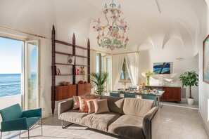 A spacious living room with a large sofa, a dining area, and a view of the sea. - Santa Caterina (Amalfi)