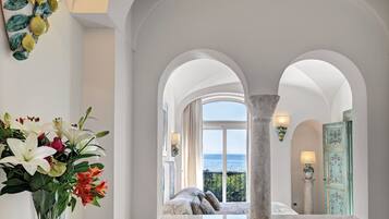 A hotel lobby with a view of the sea, a marble bench, and a vase of flowers.