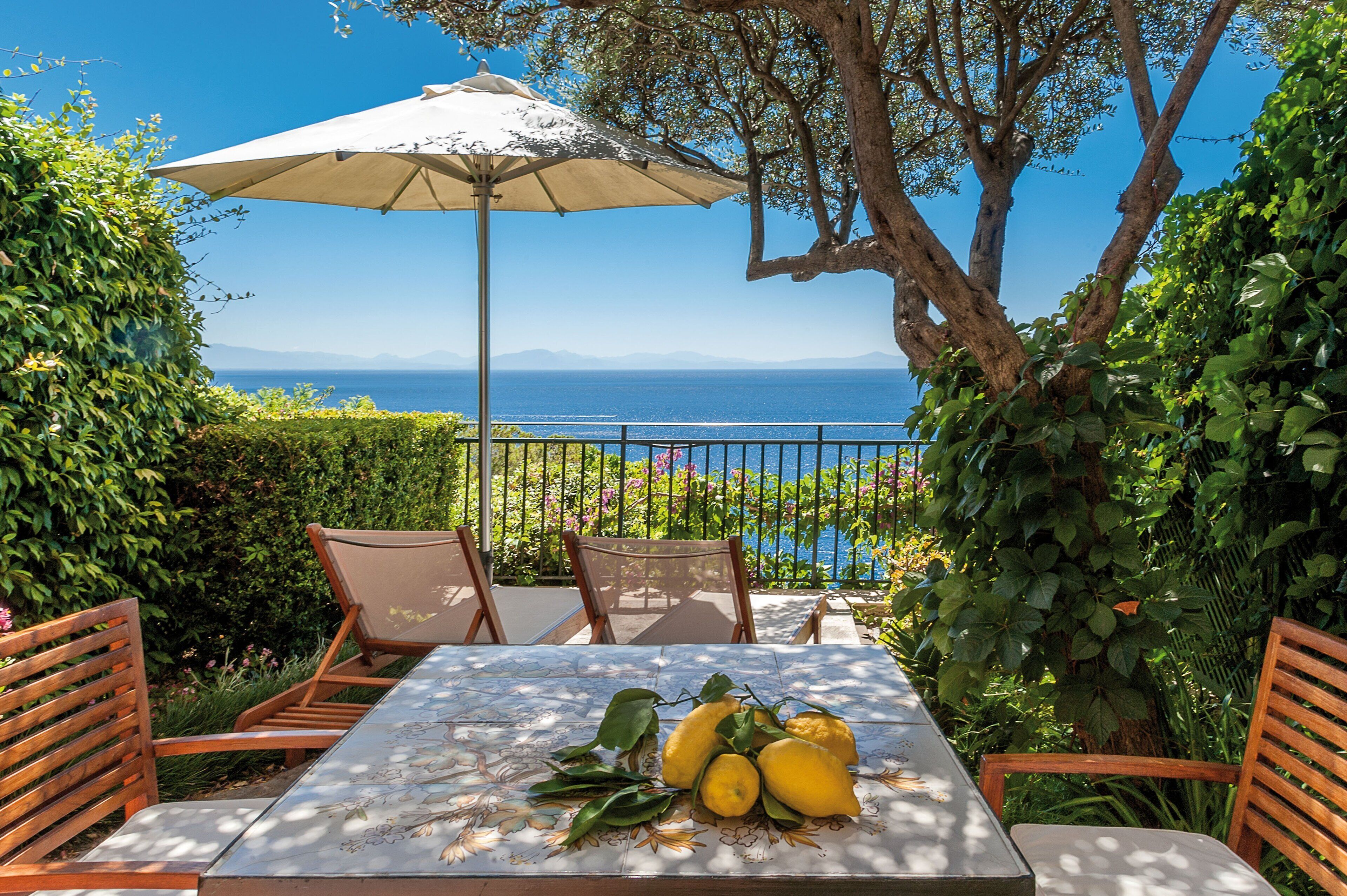 A patio with a table, chairs, and an umbrella overlooking a scenic view.