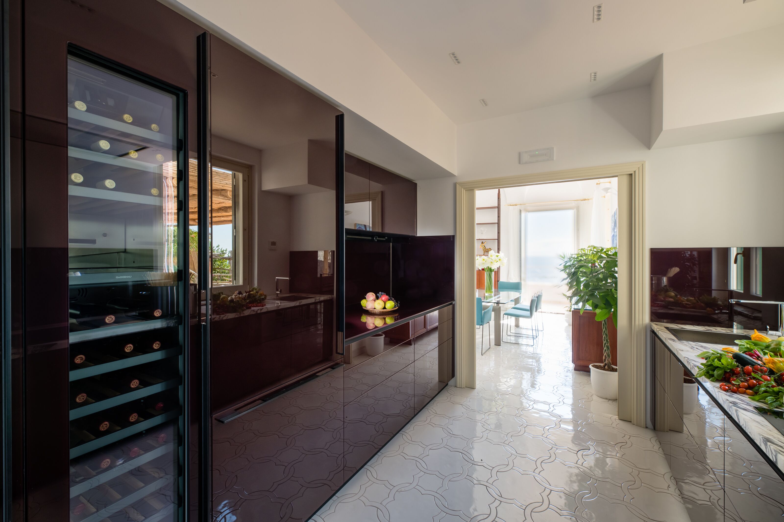 Una cocina moderna con un botellero, un frutero y una zona de comedor con una planta.