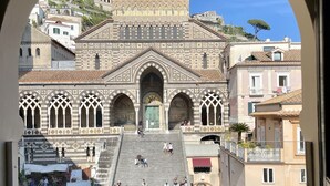 A view of a historic building with a central dome and arched windows, through an archway. - Terrazza Duomo (Amalfi)